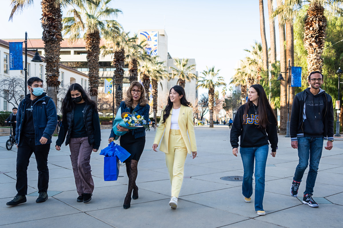 President Teniente-Matson walking down the Paseo with students.
